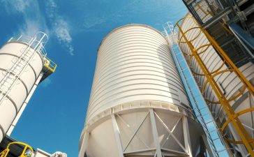 Silos industriais modernos vistos ao ar livre sob um céu azul.