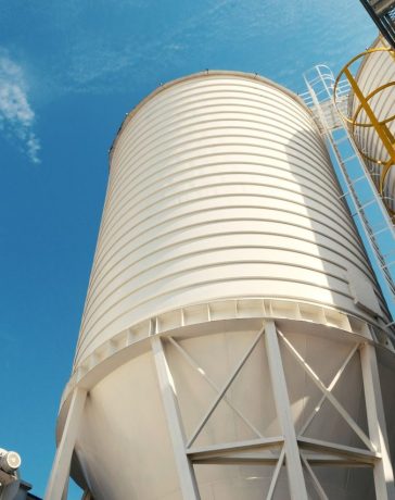 Silos industriais modernos vistos ao ar livre sob um céu azul.