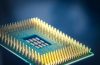 Close-up de um chip de computador com pinos dourados sobre fundo azul.