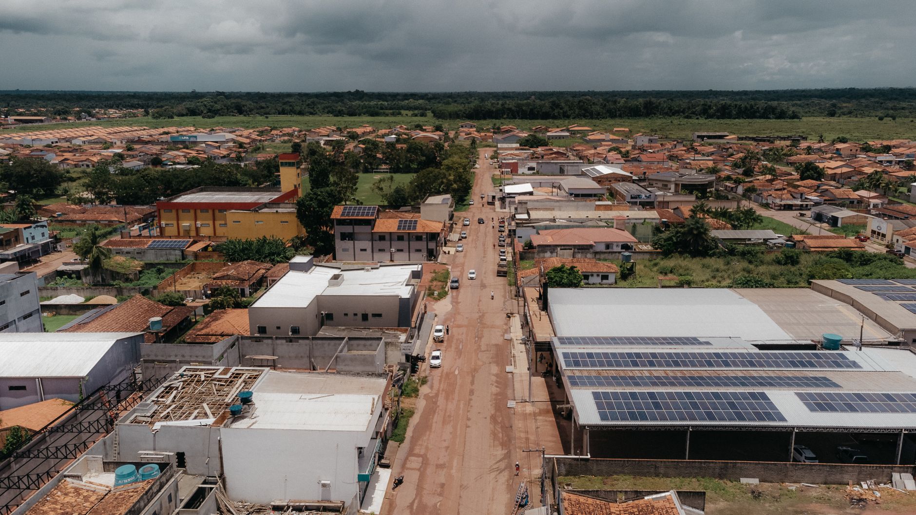 Vista aérea de uma comunidade amazônica com painéis solares instalados nos telhados, cercada por áreas verdes.